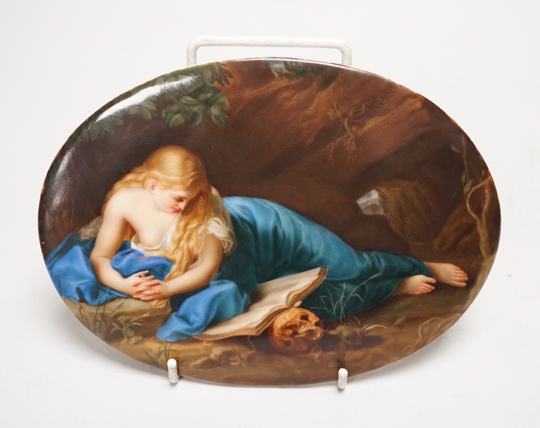 A 19th century painted porcelain oval plaque of a reclining lady reading a book. The reverse stamped L. Sturm Dresden. 15x19.5cm